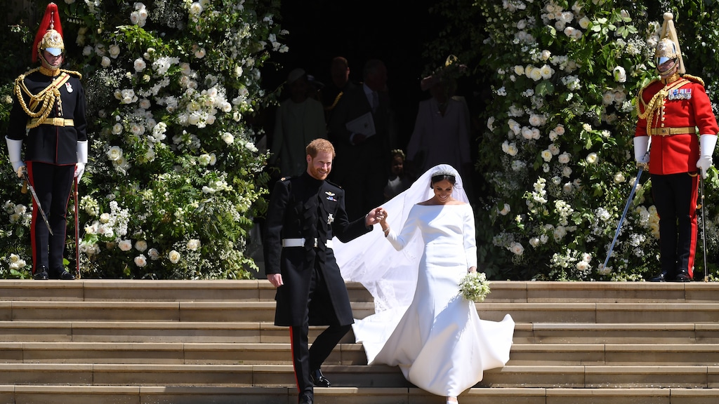 Meghan Markle loopt in haar jurk met prins Harry de trap af.