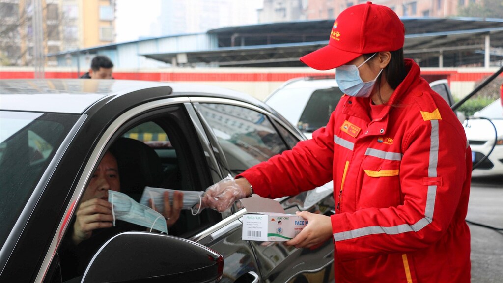 Bij een pompstation in het Chinese Chongqing worden mondkapjes uitgedeeld.