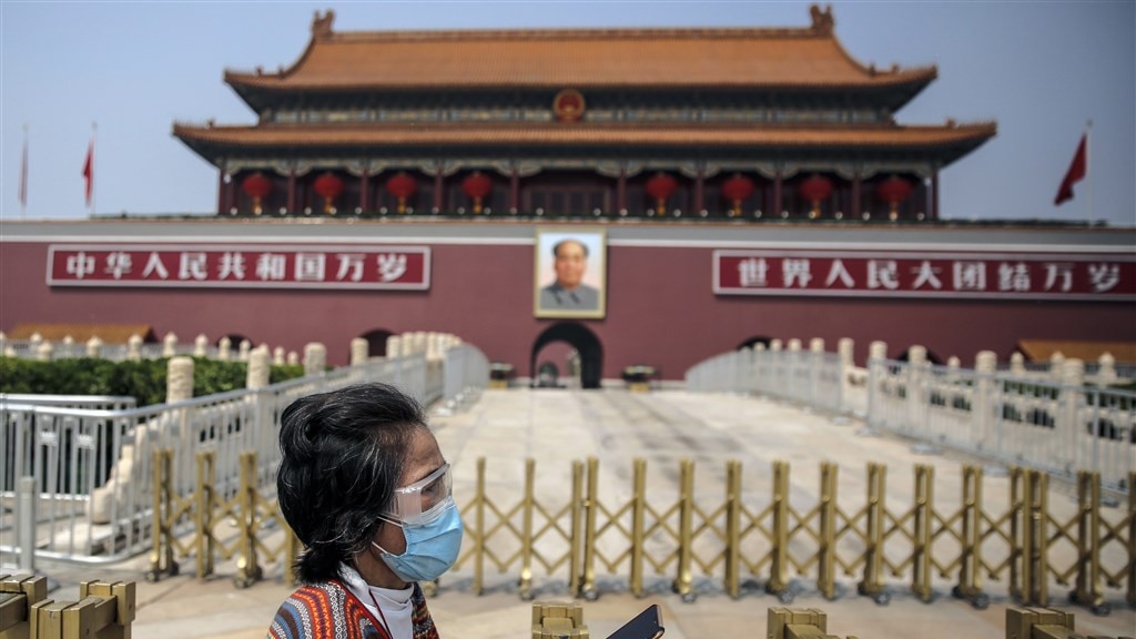 Een vrouw draagt beschermingsmiddelen op het Tiananmen Plein in Beijing.