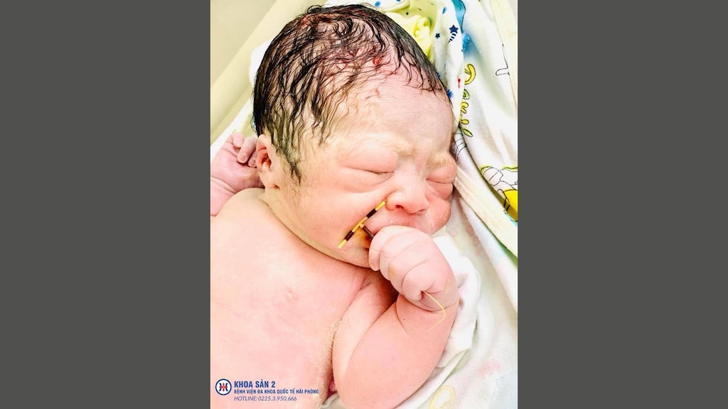 Pasgeboren baby poseert met spiraaltje in de hand in Vietnamees ziekenhuis