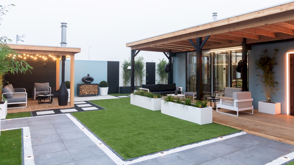 Comfortabele stoelen en banken rondom een kunstgrasmat: de tuin van het Big Brother-huis.