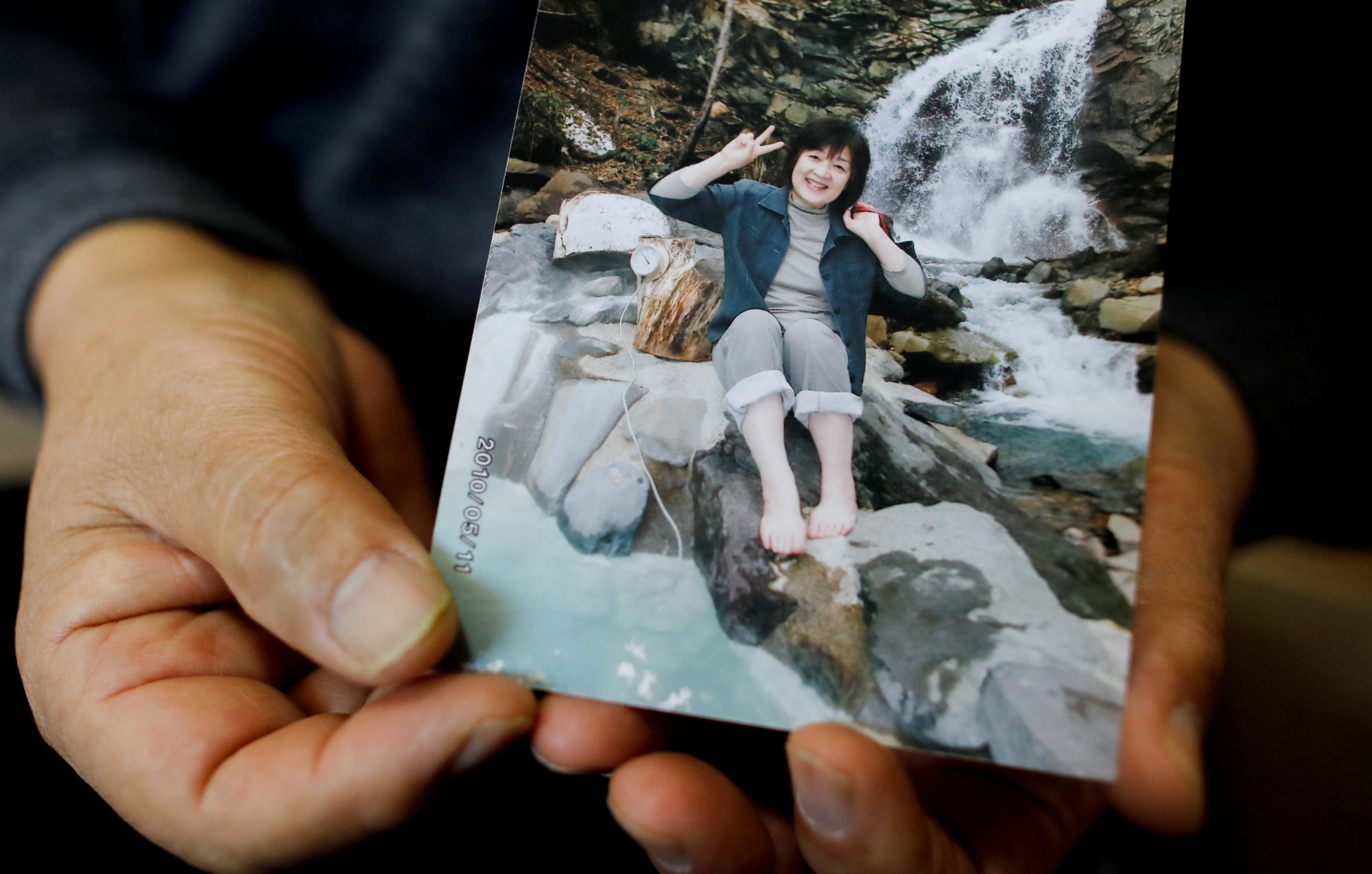 Kazuyoshi Sasaki houdt een foto van zijn overleden vrouw vast.