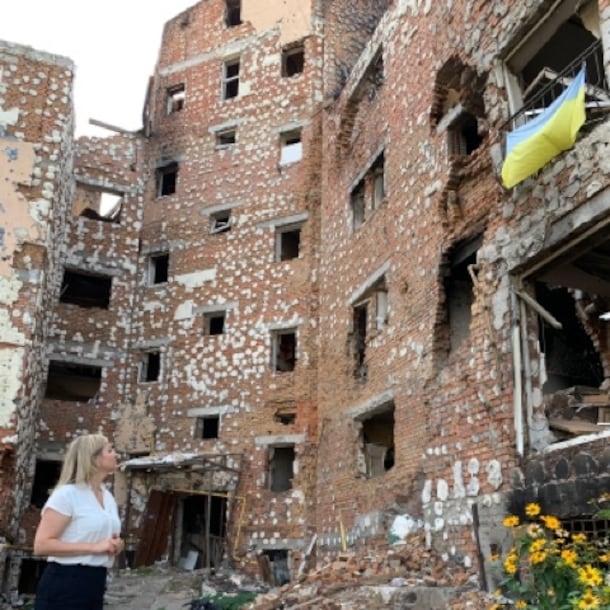 Minister Schreinemacher bekijkt een verwoest gebouw.