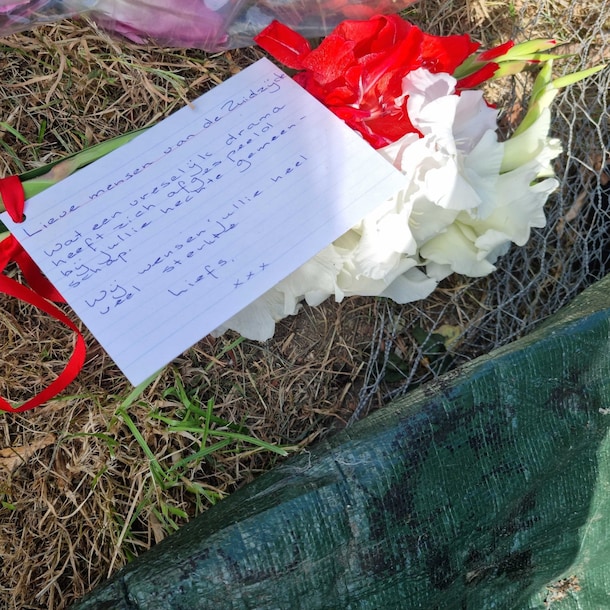 Bloemen met troostende woorden op de plek van het ongeluk.