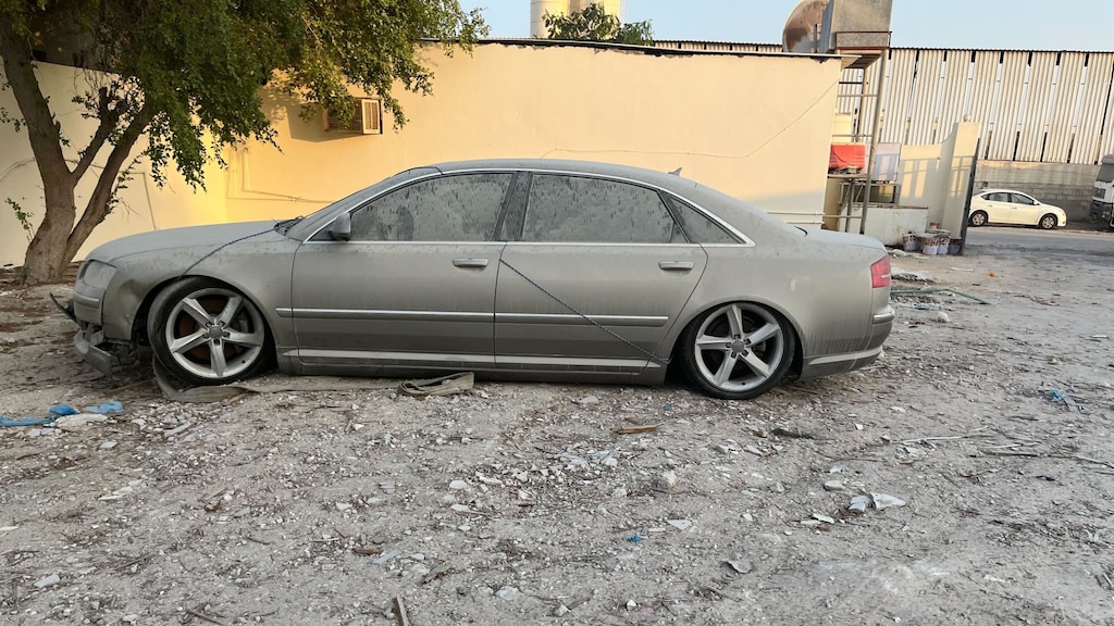 Een oude auto staat te verstoffen in het werkkampje.
