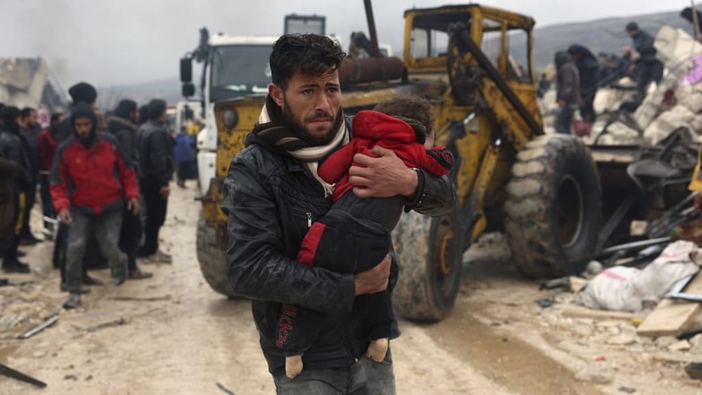 Een man draagt het lichaam van een kind weg uit de puinhopen in de Syrische stad Besnia