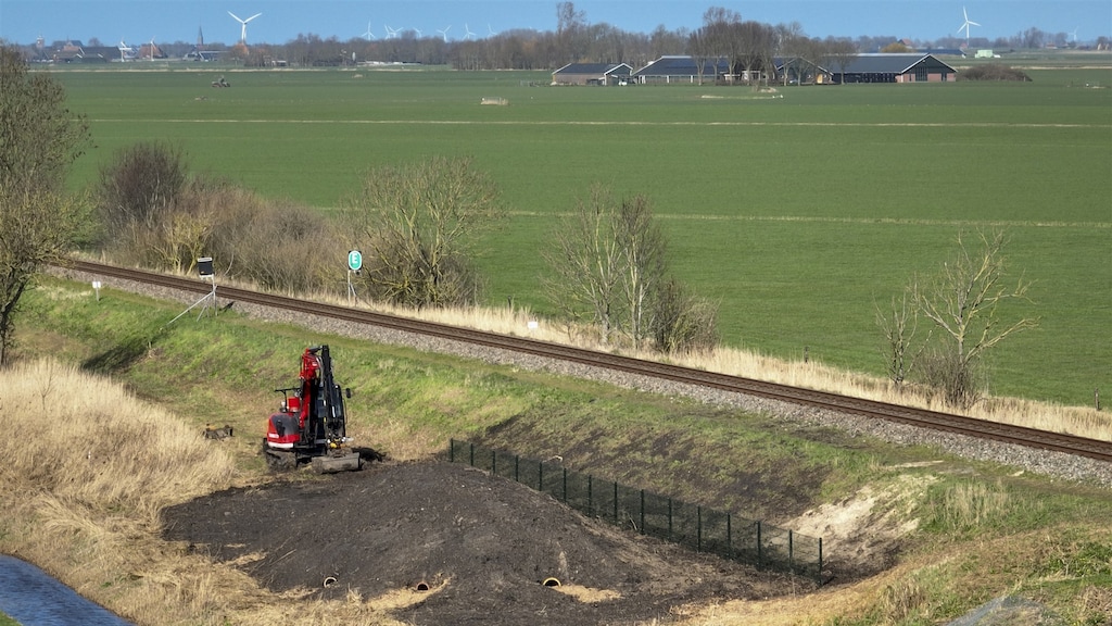 Een graafmachine langs het Friese spoor aan het werk.
