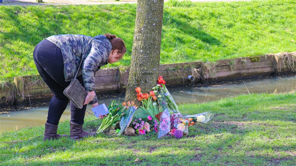 Een vrouw legt bloemen neer.