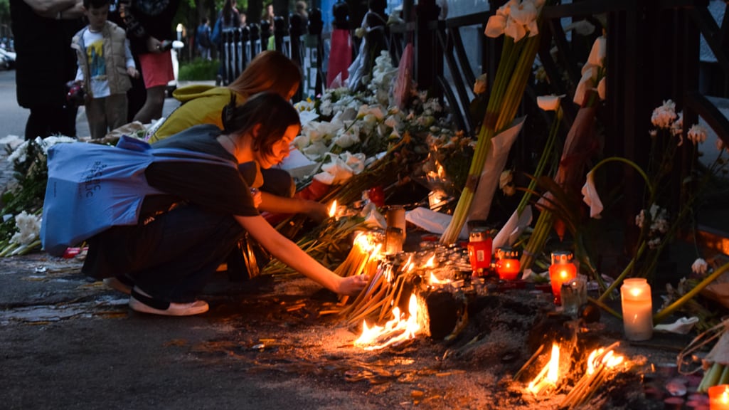 Twee jonge vrouwen steken kaarsjes aan voor de school waar de schietpartij plaatsvond.
