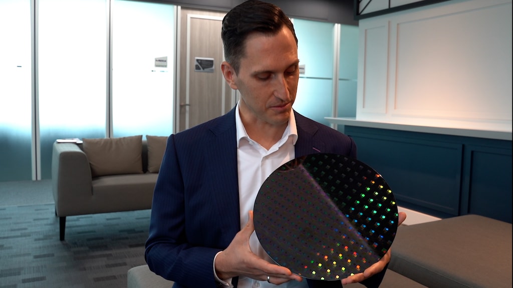 Benjamin Hein laat een wafer zien. Het zijn de ronde schijven van silicium die met een lang en complex proces uiteindelijk verwerkt worden tot computerchips.