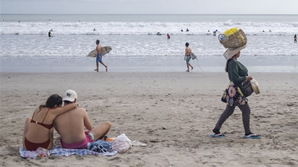 Toeristen en verkoper op strand Bali.