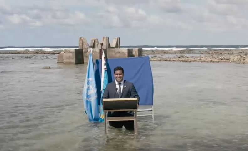 Simon Kofe van Tuvalu houdt zijn beroemde speech in het water.