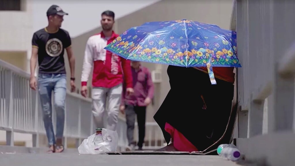 Een Saoedische bedelaarster probeert zich te beschermen in de zon.