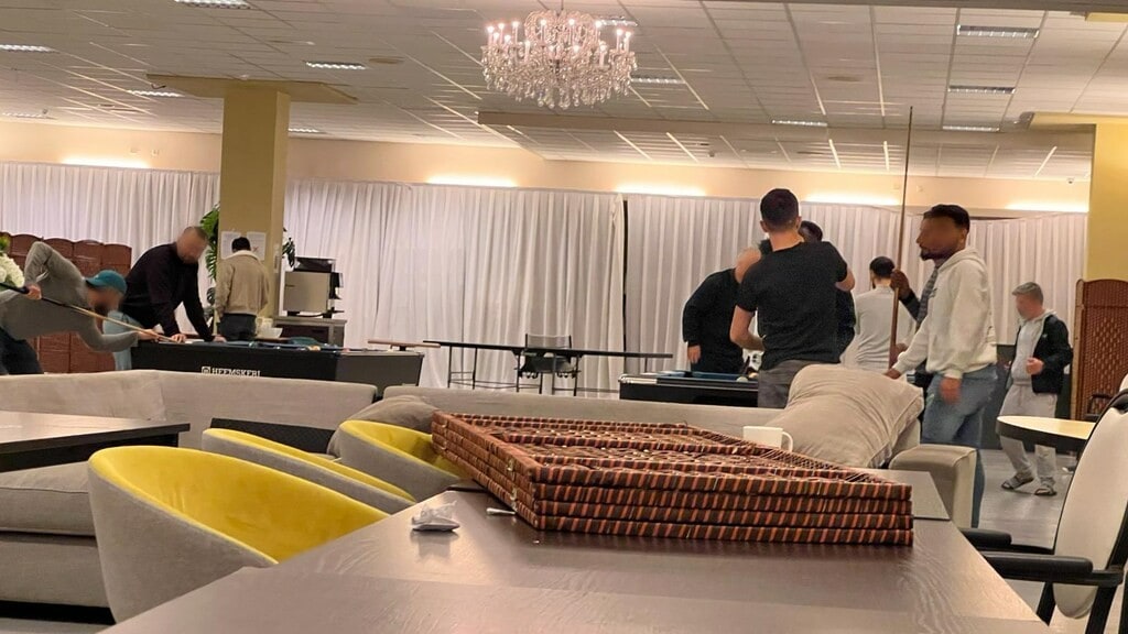 Bewoners van de noodopvang in een zaal waar ze biljart kunnen spelen