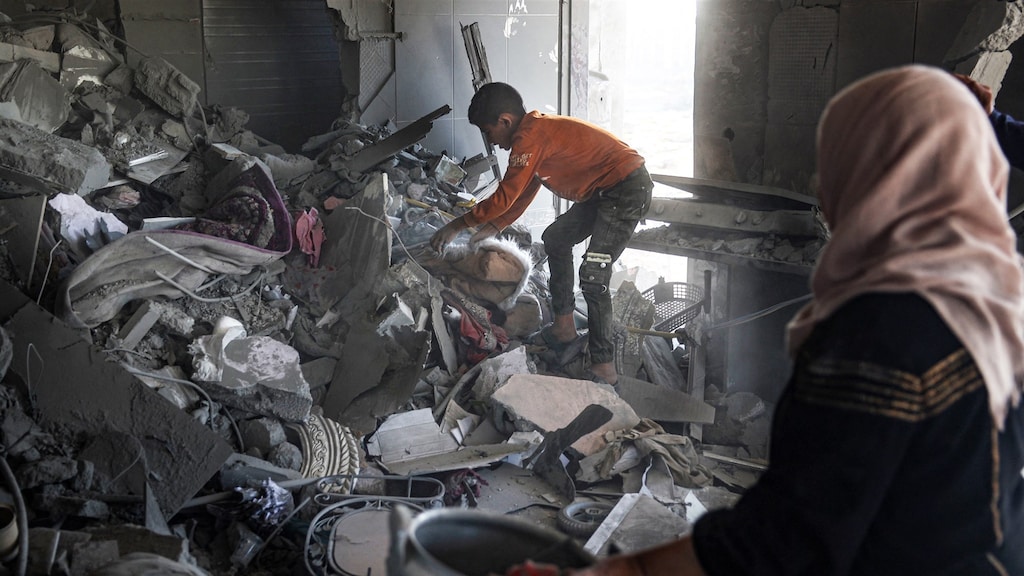 Een Palestijnse vrouw en kind zoeken tussen het puin veroorzaakt door de luchtaanval op Rafah naar persoonlijke bezittingen.