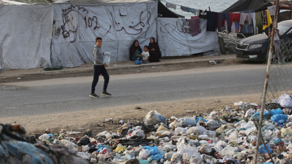 Mensen slapen pal naast grote bergen afval.