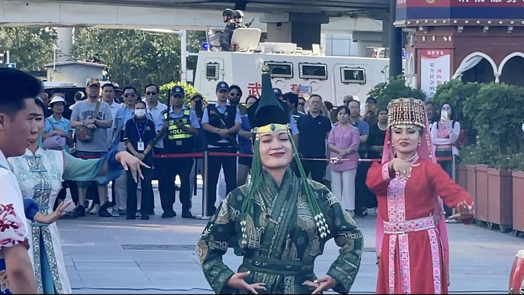 Toeristen verdringen zich om traditionele Oeigoerse dans te bekijken. Politie en leger zijn overal zichtbaar.