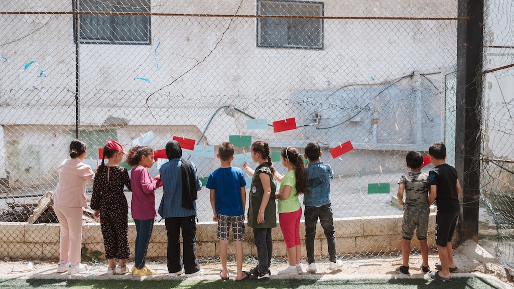 Kinderen bij een hek met briefjes tijdens een van de sessies van Right To Play.