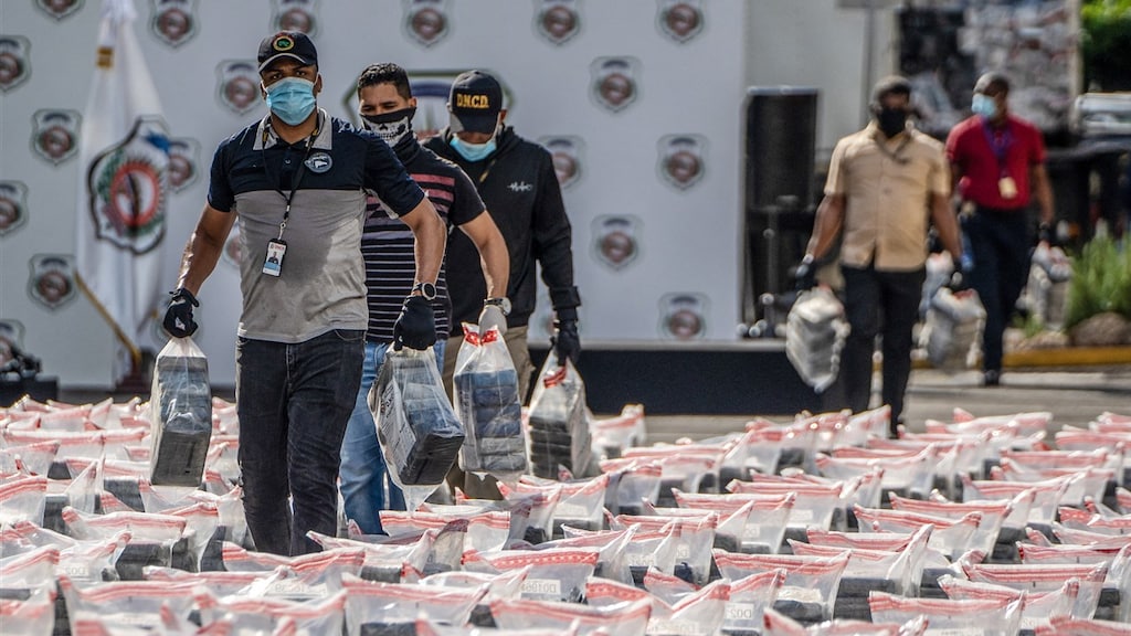 Leden van het anti-drugskorps dragen pakketten met vermoedelijke drugs