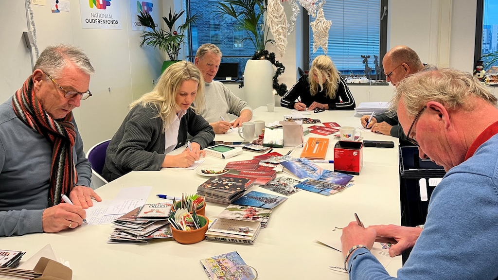 De vrijwilligers helpen met het schrijven van kerstkaarten, met links Elien.