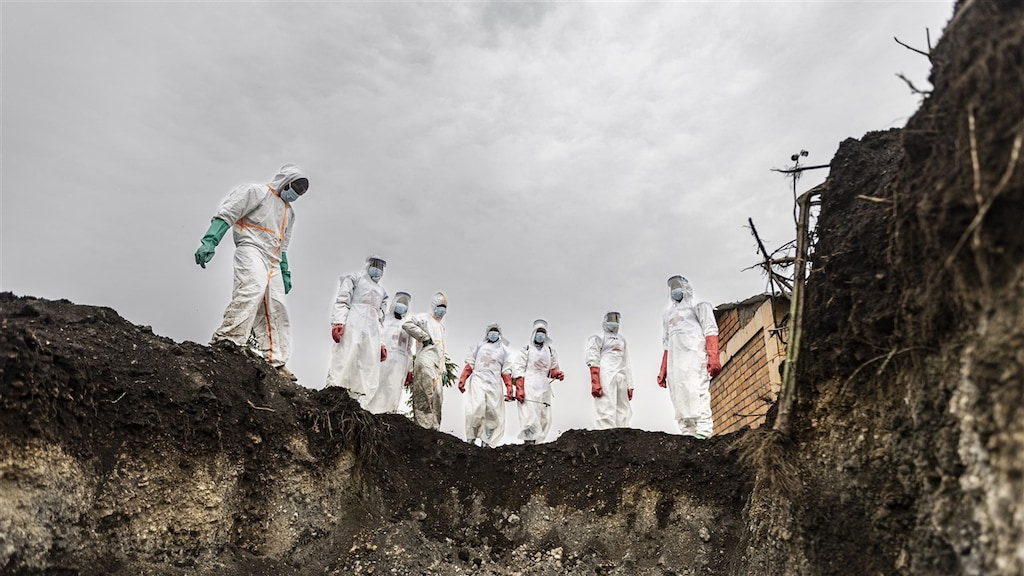 Mensen staan aan de rand van nieuwe graven op de begraafplaats van Goma.