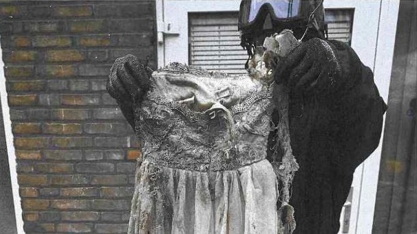 Een brandweerman houdt een half verbrande trouwjurk omhoog uit de winkel Aliyahs Styling.