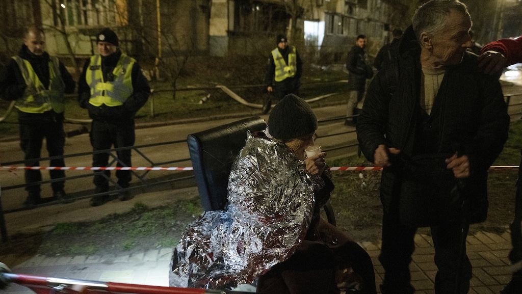 Een oudere vrouw wordt buiten opgevangen.