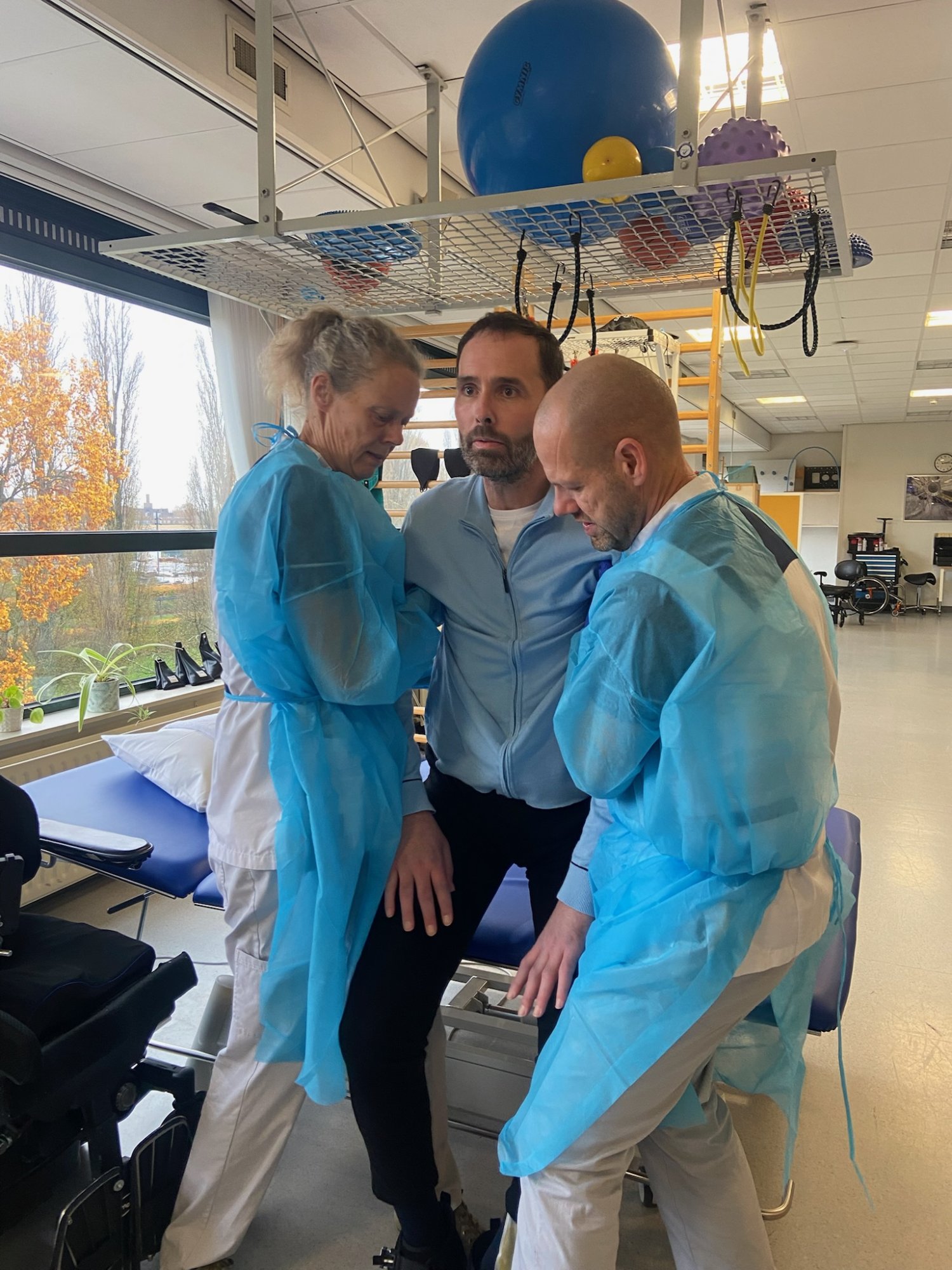 In het revalidatiecentrum wordt Albert door fysiotherapeuten getraind om met behulp van anderen te staan.