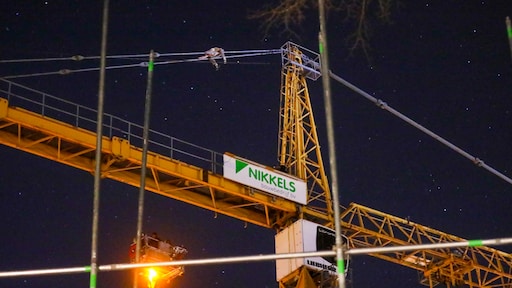 Man klimt in hijskraan en blijft urenlang zitten, tientallen toeschouwers