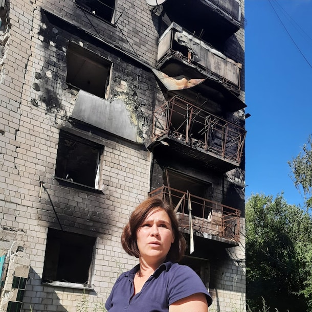 Arenda Vasylenko staat bij een gebouw dat gebombardeerd is door Rusland in de stad Borodyanka ten westen van Kyiv.