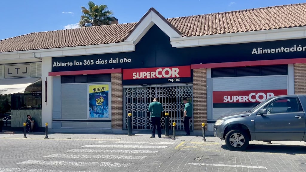 Twee bewakers houden de wacht bij een gesloten supermarkt in een winkelcentrum waar na de stroomuitval iedereen vertrokken is.