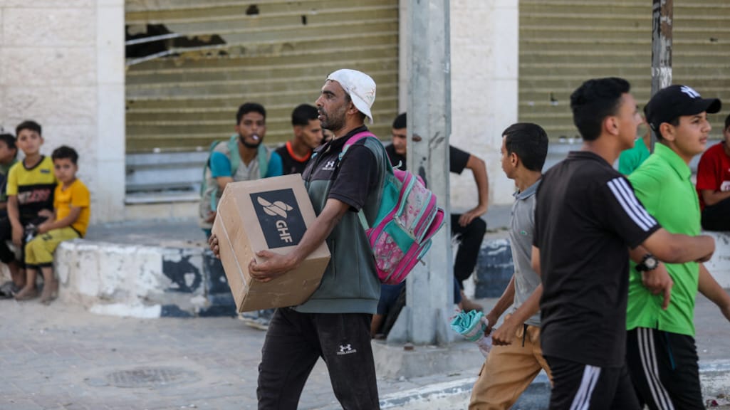 Een Palestijnse man loopt door de Netzarim corridor met hulpgoederen van de GHF.
