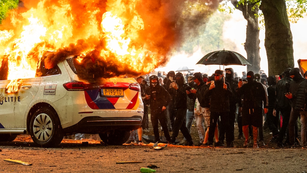 Een politiewagen die in brand is gestoken door relschoppers