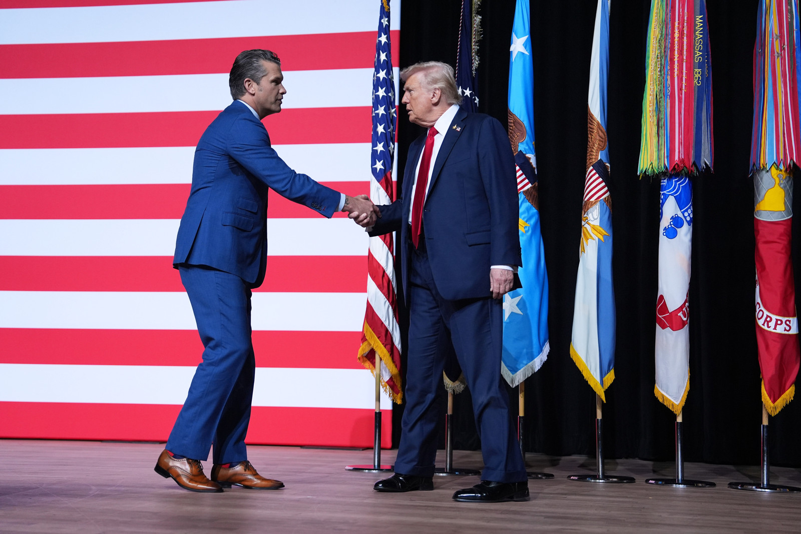 Hegseth verwelkomt na zijn toespraak president Trump op het podium.