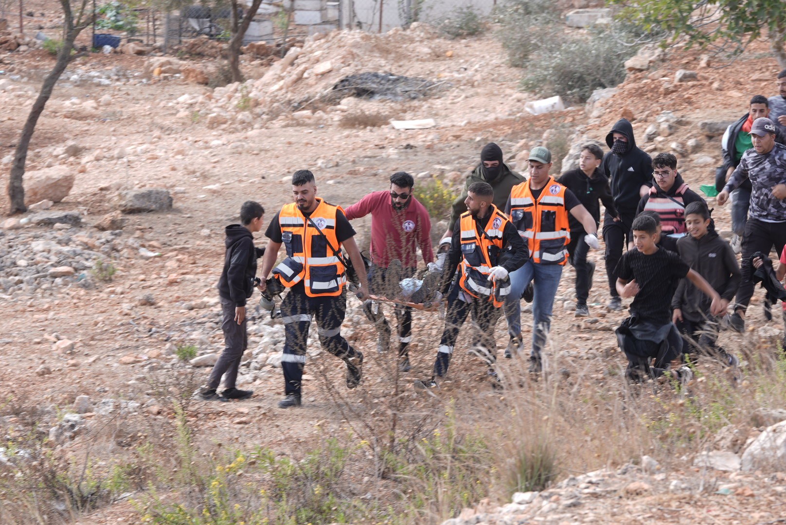 Hulpverleners dragen een jongeman op een brancard nadat hij in zijn been is geschoten buiten de gevangenis Ofer.