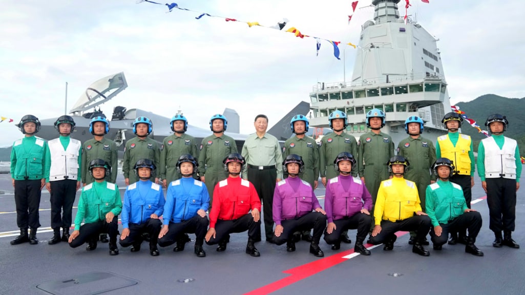 Xi (midden), gekleed in een groen hemd en pantalon.