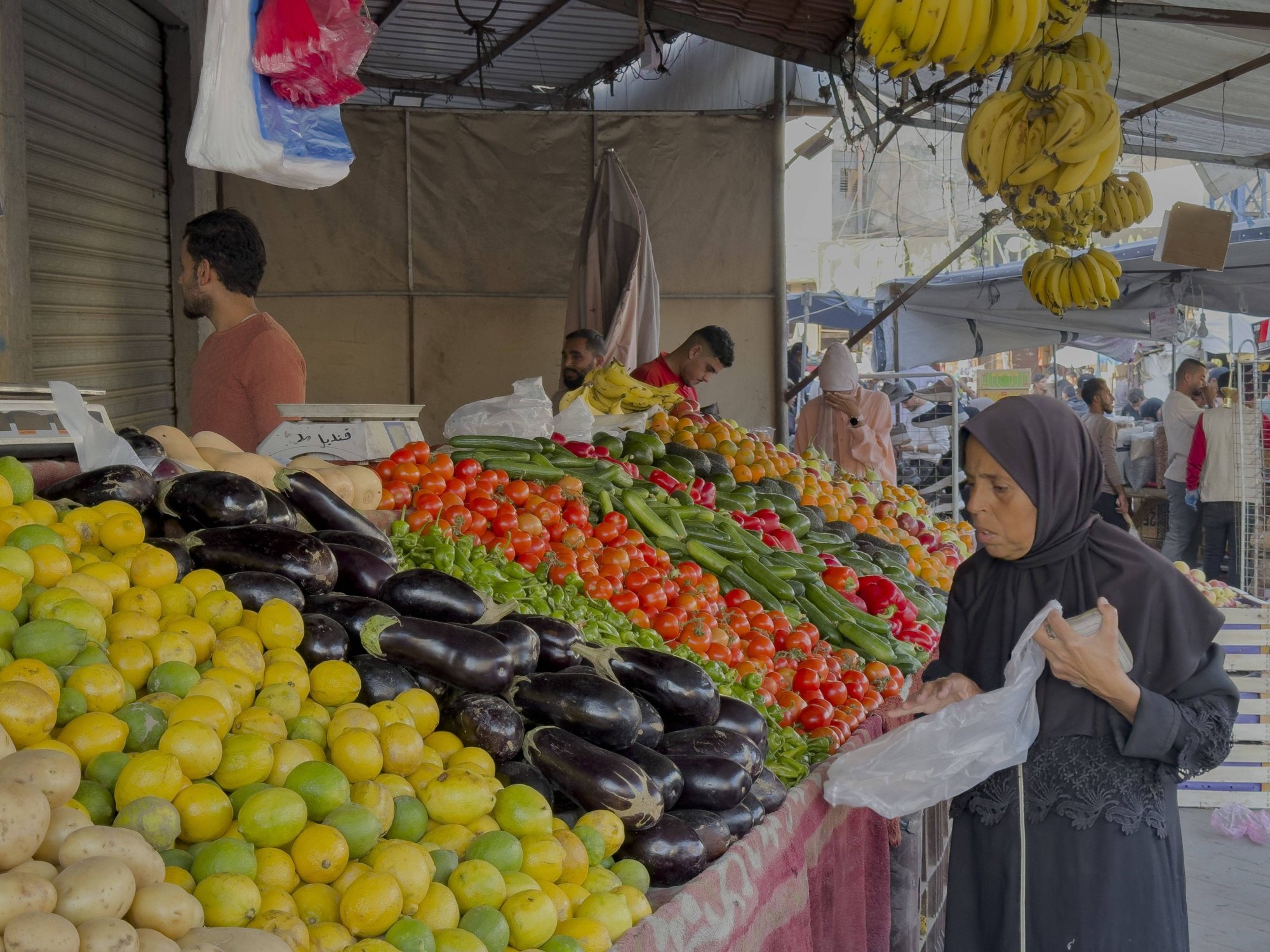 Een vrouw koopt groenten bij een marktkraam in Deir al-Balah.
