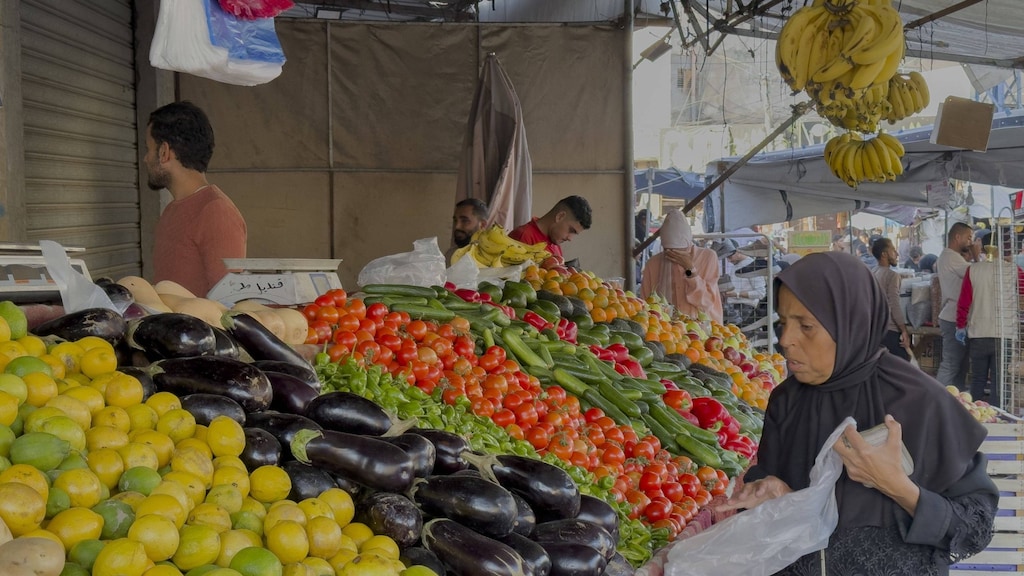 Een vrouw koopt groenten bij een marktkraam in Deir al-Balah.