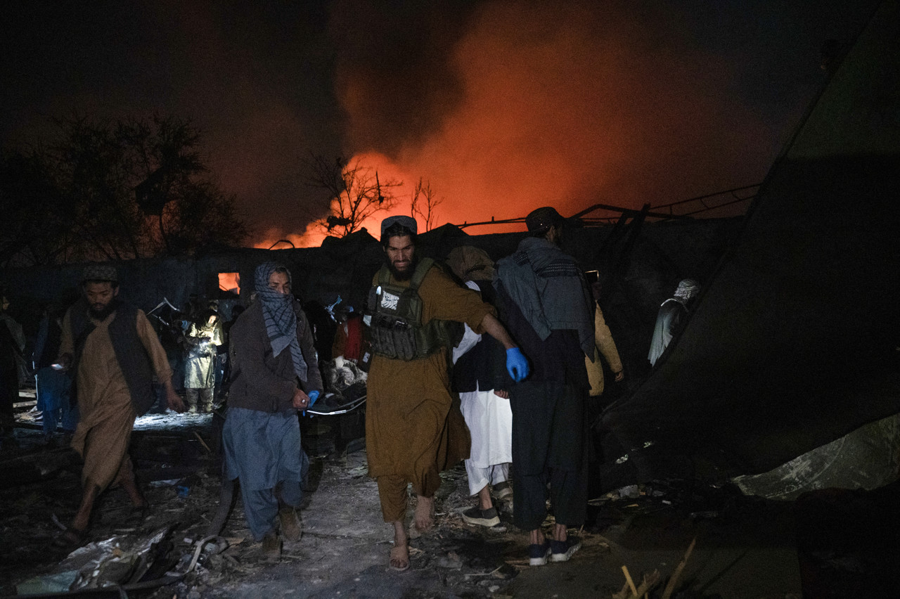Taliban-beveiligers dragen een lichaam weg op de plek van de aanval.