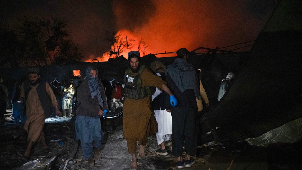 Taliban-beveiligers dragen een lichaam weg op de plek van de aanval.