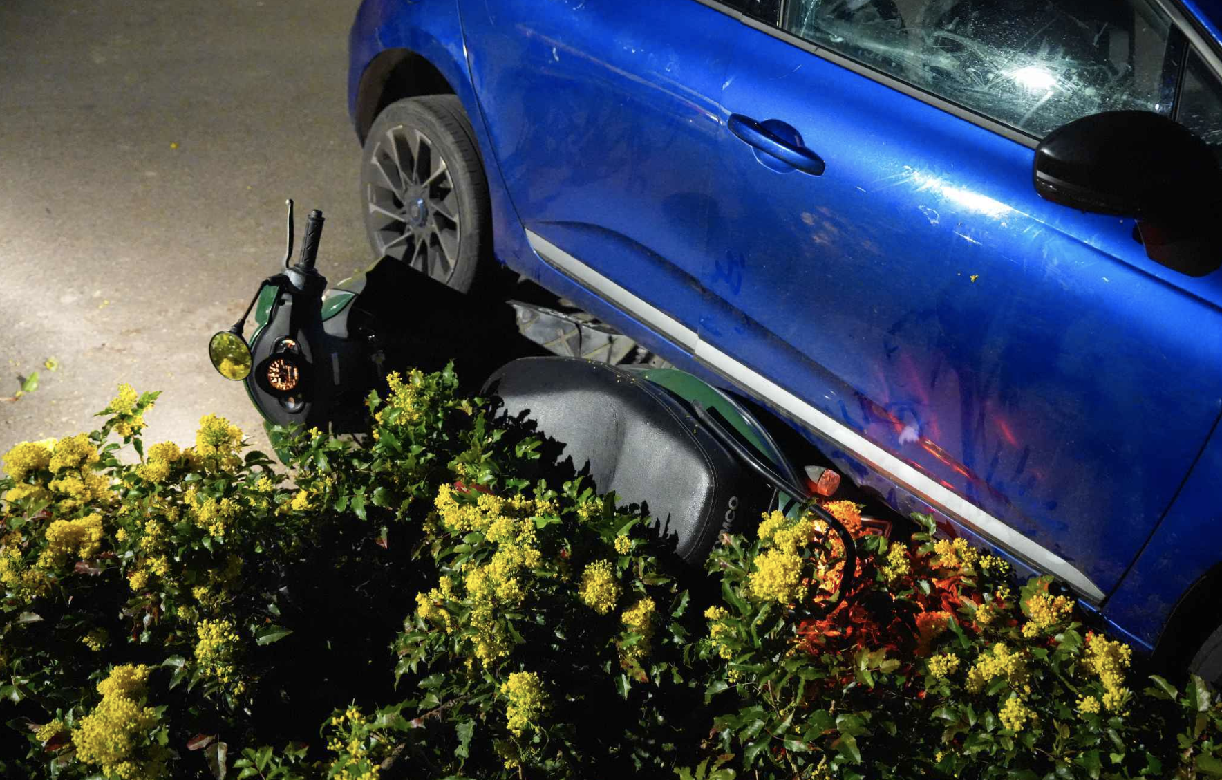 De scooter werd deels onder de auto gevonden.