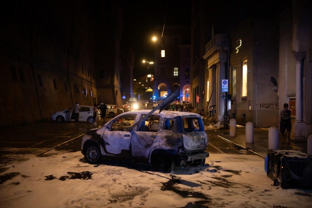 Een uitgebrande auto in Bologna na de protesten tegen Fakirs dood.