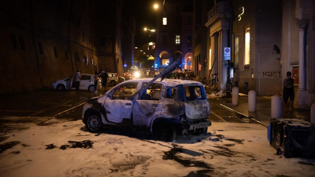 Een uitgebrande auto in Bologna na de protesten tegen Fakirs dood.